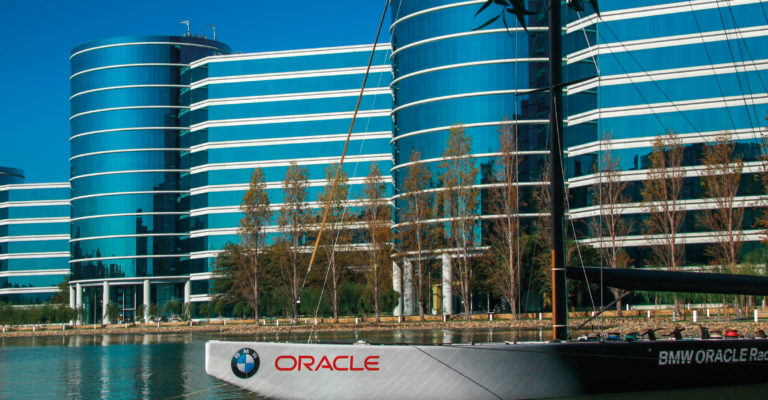 A boat with  BMW and Oracle logos in front of the glass building