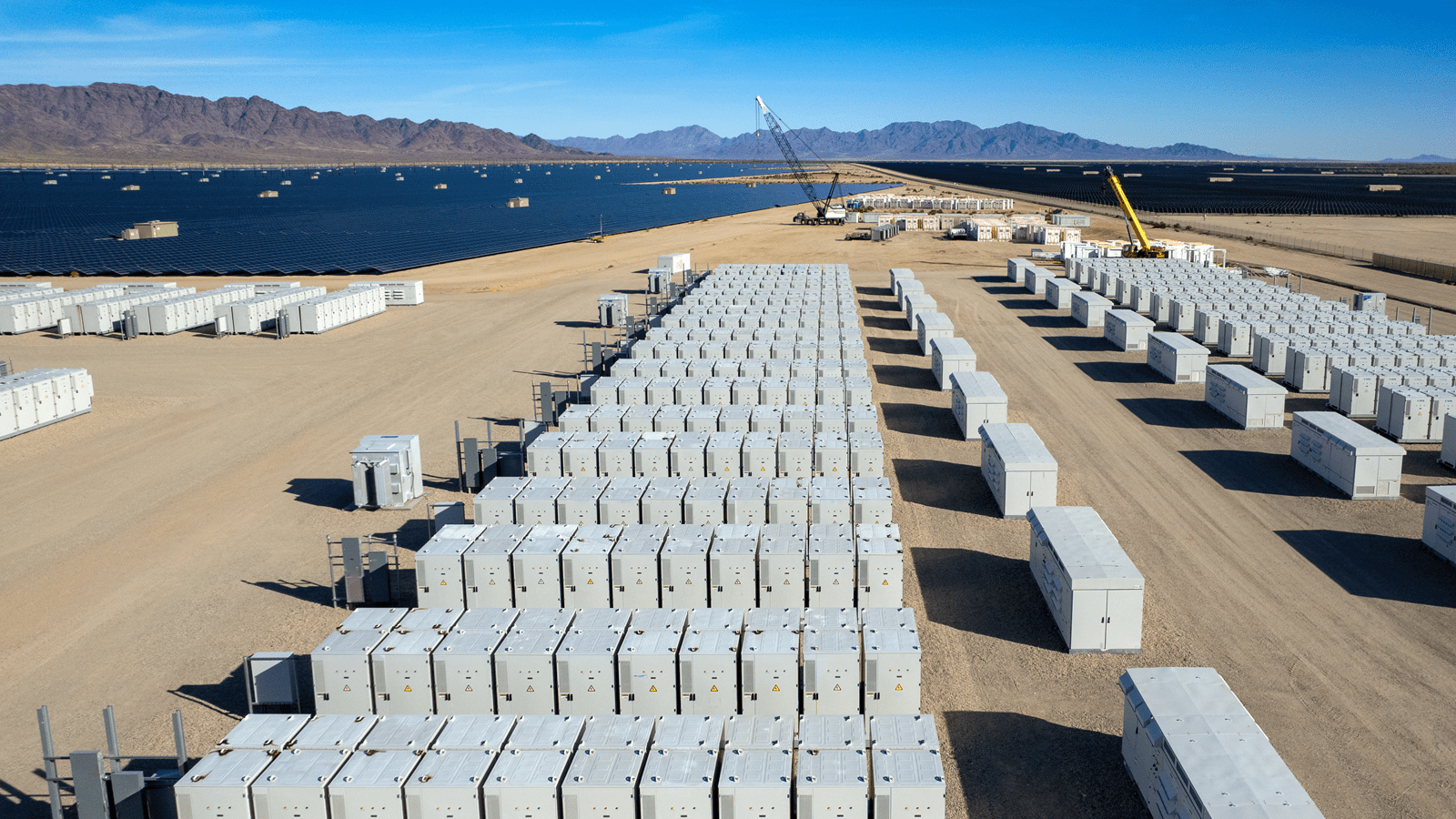 Battery energy storage crates nearby a field of solar panels