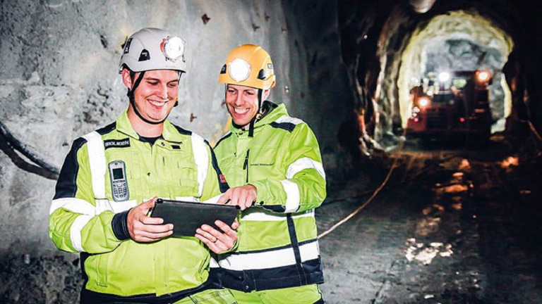 Two miners in a shaft overseeing mining process via tablet