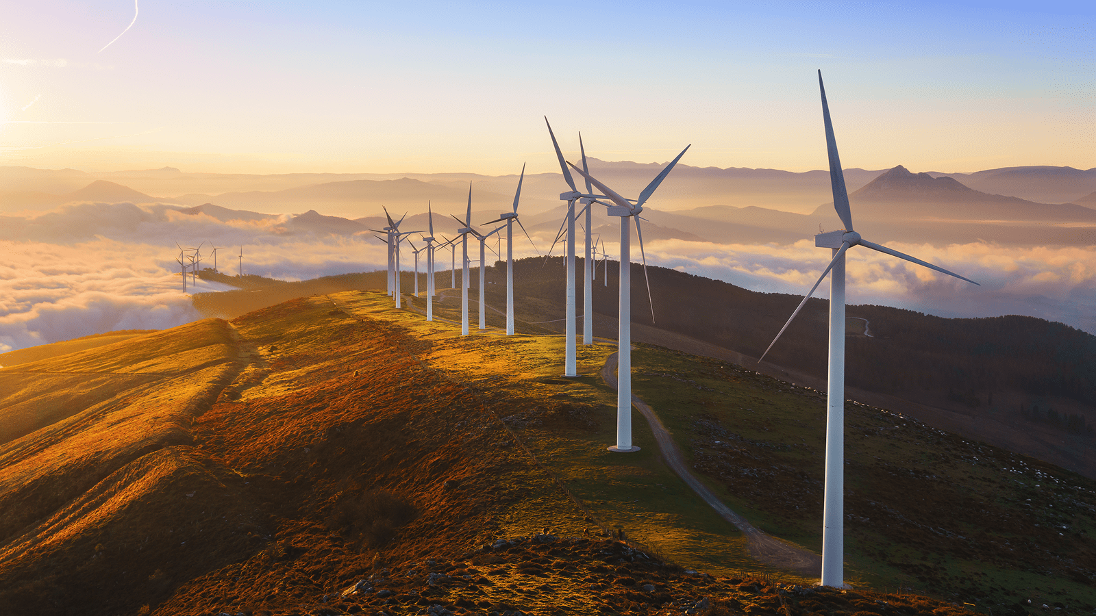 Wind turbines in a row on a ridge above the clouds